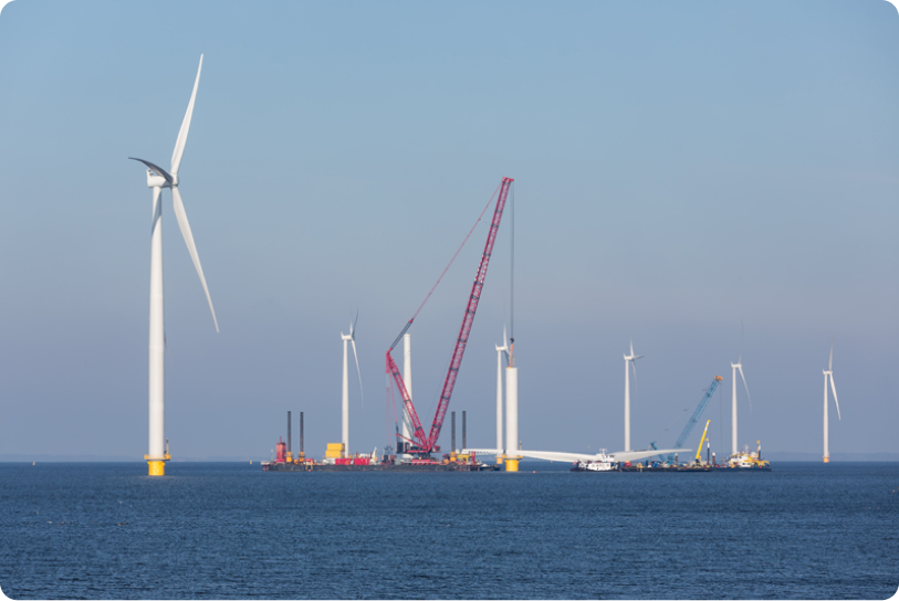 A photo showing a windfarm under construction in the sea.