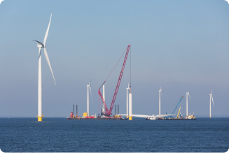 A photo showing a windfarm under construction in the sea.